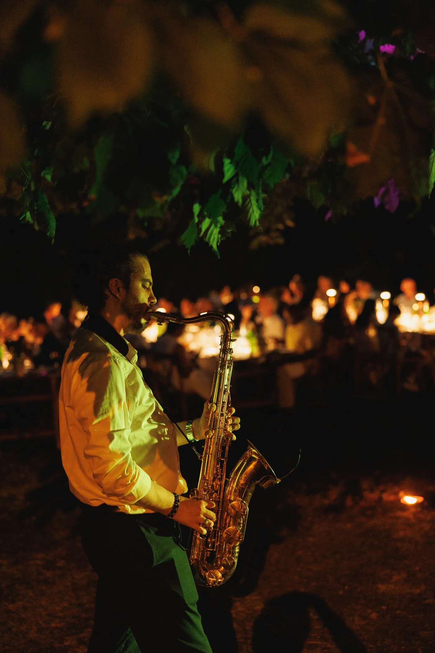 Pietro suona il sax di sera, con le candele dei tavoli sullo sfondo